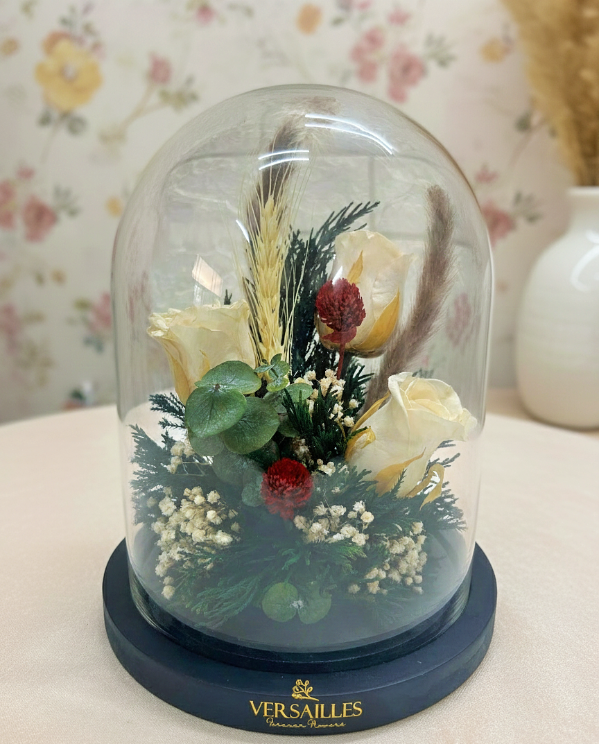 Decorative glass dome with preserved flowers and greenery on a floral-patterned background