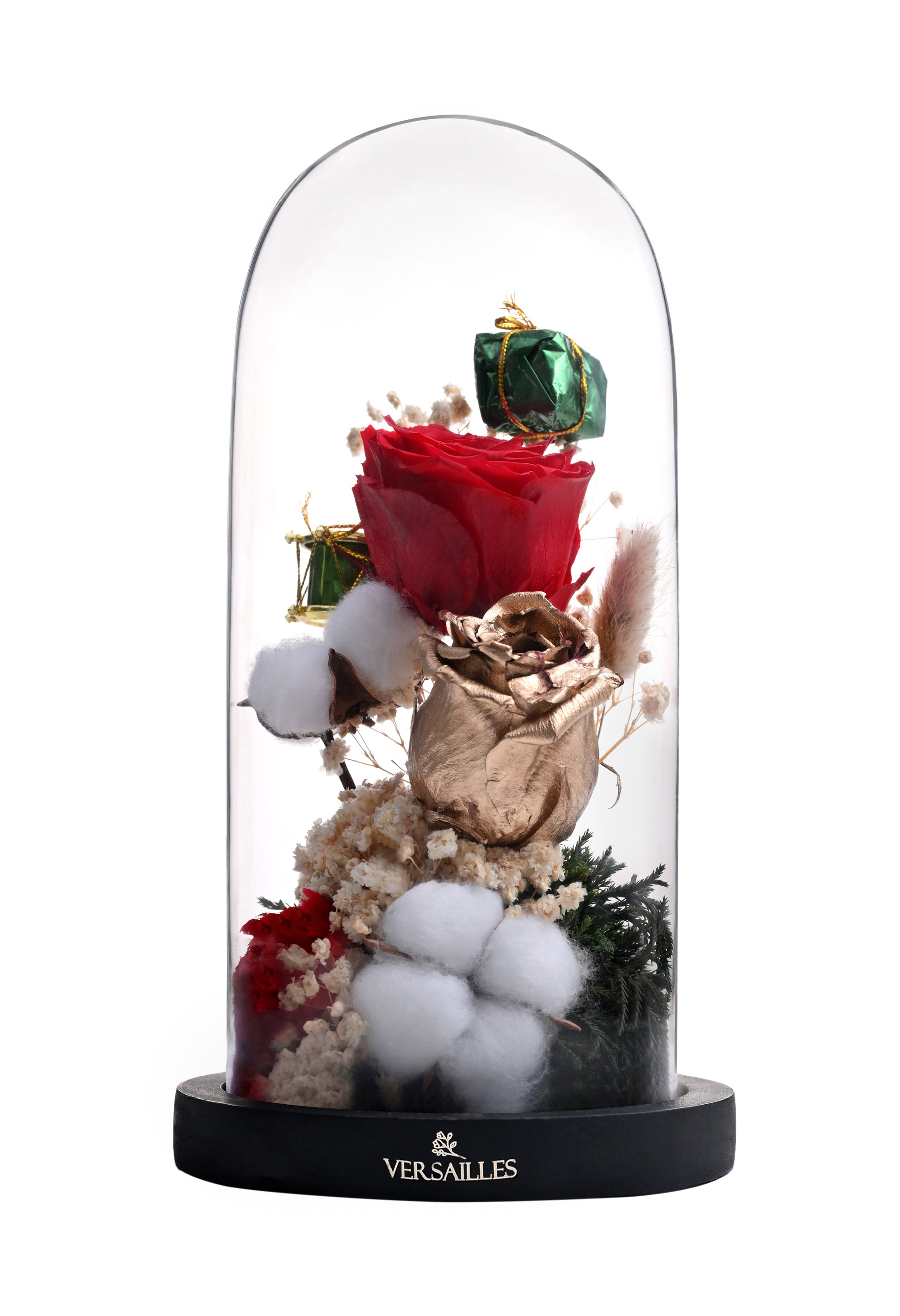 Decorative display with red rose, white cotton, and green gem under a glass dome with 'Versailles' branding.